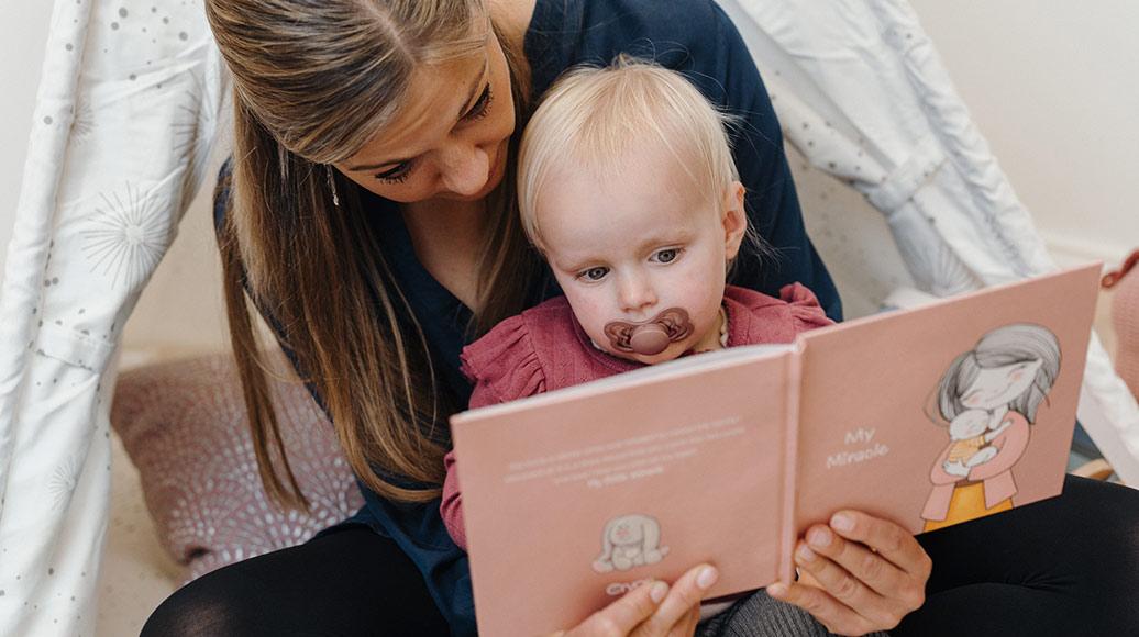 Mother and daughter reading book about donor sperm treatment