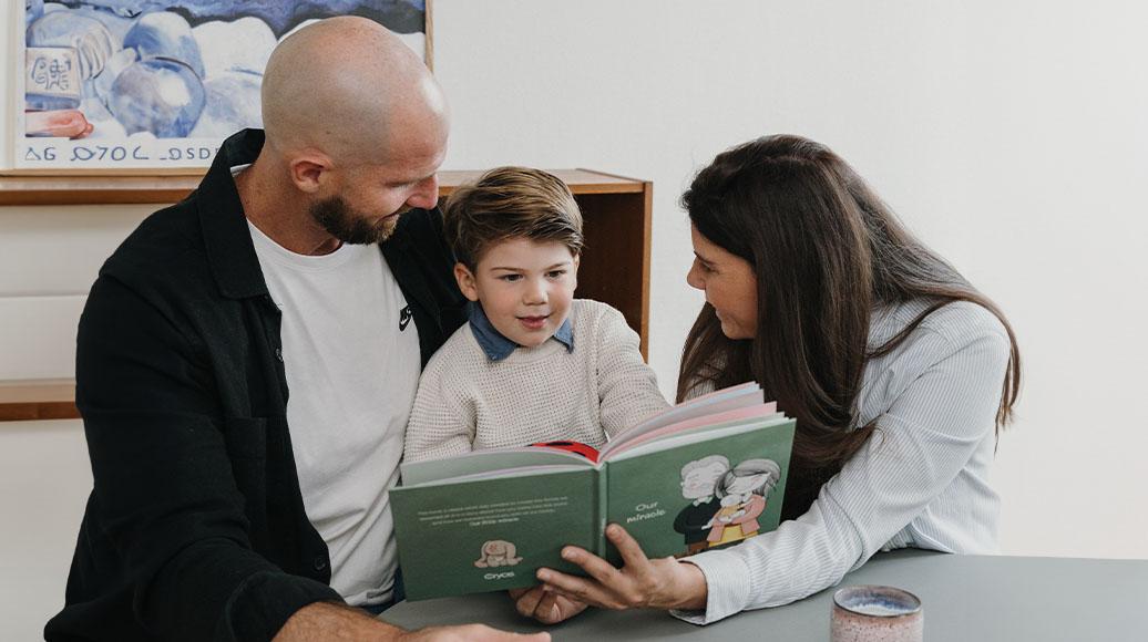 Familie med donorbarn sidder og læser en bog